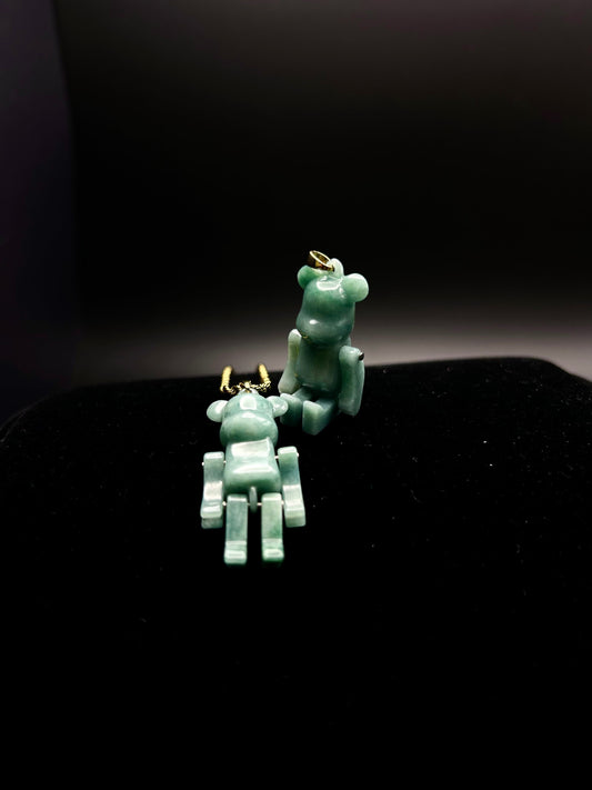 Two jade bear-shaped pendants on a dark background